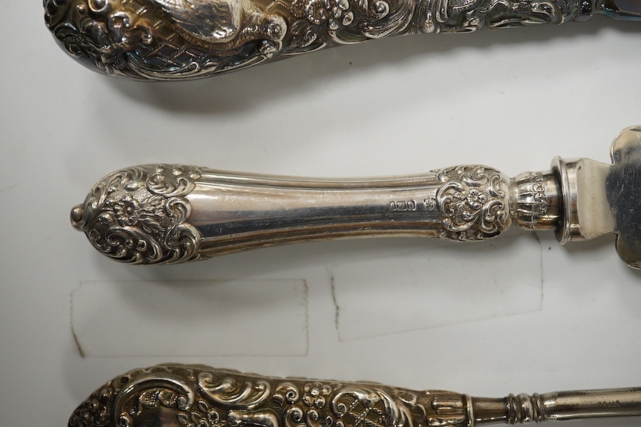 An Edwardian silver cake knife with engraved blade and decorative handle, James Deakin & Sons, Sheffield, 1901, together with a late Victorian silver handled button hook and silver handled shoe horn. Condition - poor to